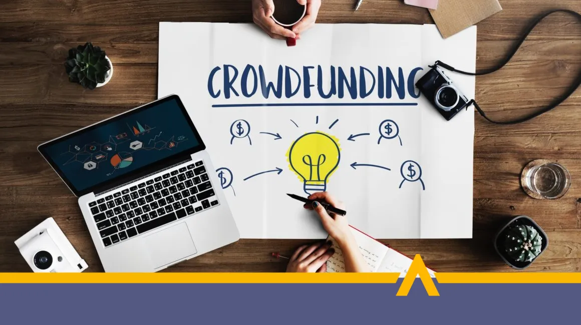 Plansza z napisem crowdfunding obok laptop i aparat